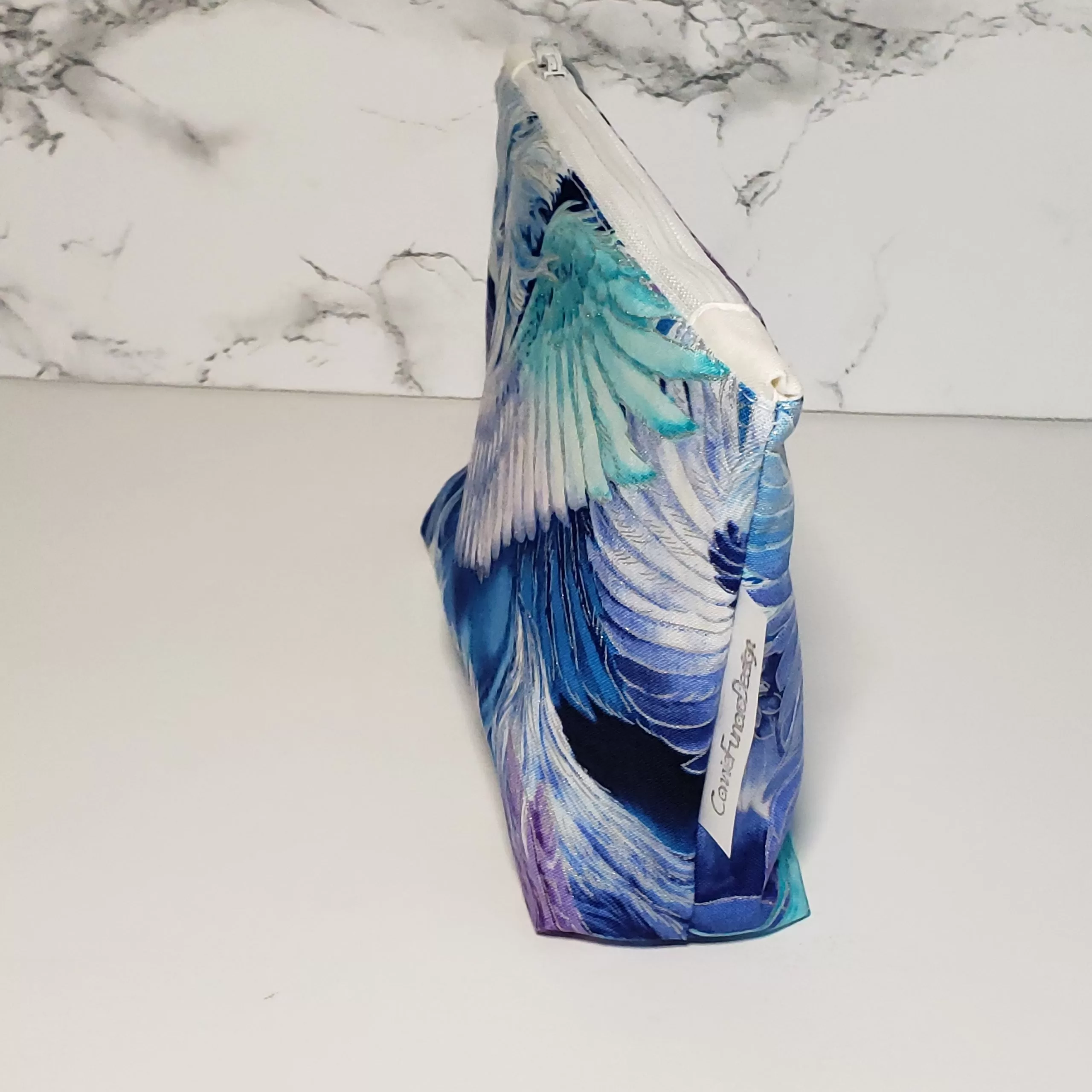 Pegasus mystical creature theme with metallic fabric accents. Structured box bottom accessory bag. Lined with white fabric and matching zipper. Convenient zipper pull. 100% Cotton fabric. Measures 8.5 inches wide, 5 inches tall.