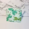 Small green dragonfly pattern accessory bag with front window pocket for makeup remover wipes. Fully lined interior. Zip closure with attached keyring. Measures 6 inches wide. Window pocket allows easy access to a packet of wipes (not included).