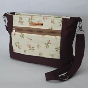 Handmade floral purse in cream and pink with espresso trim, adjustable strap, dual exterior zip pockets, and zipper closure.