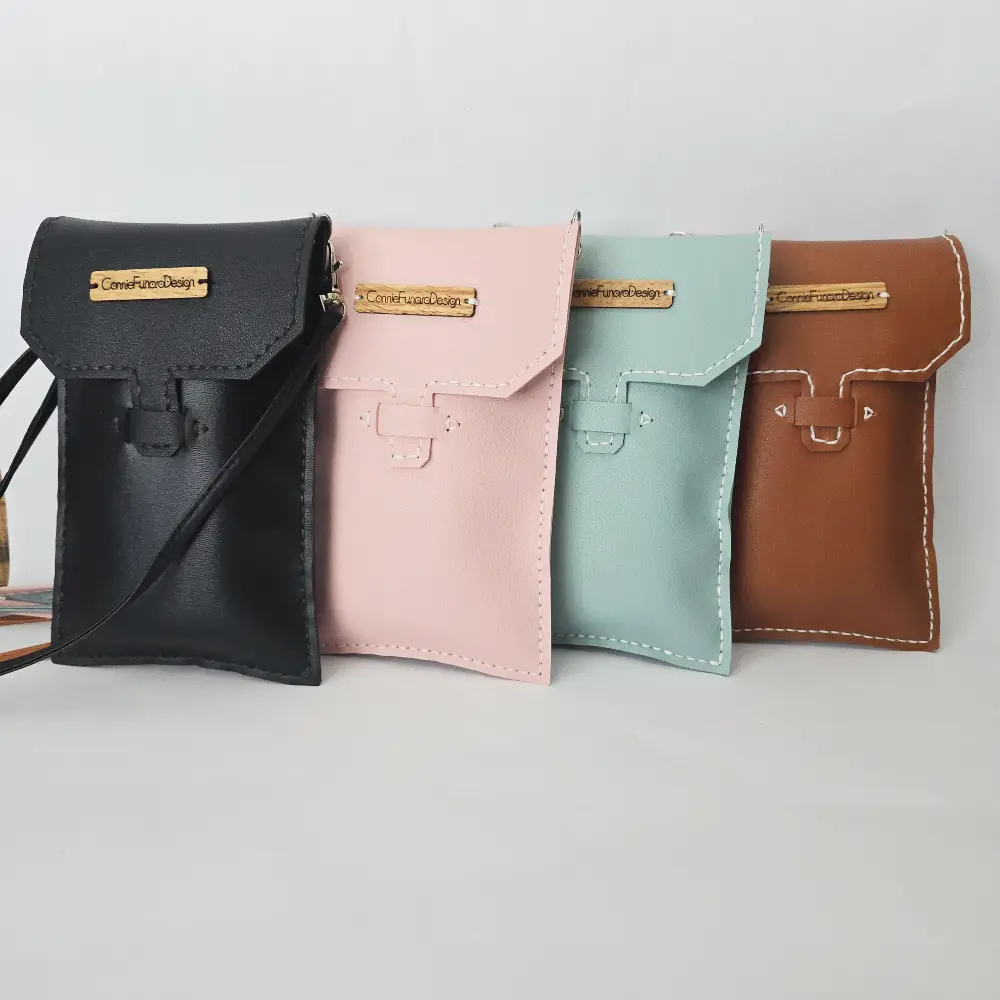 Handmade crossbody phone bag in vegan leather, 7.5 inches tall, available in pink, blue, brown, and black, with adjustable strap for a comfortable fit.