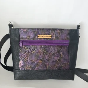 Purple dragonfly embossed vegan leather purse with black trim and adjustable shoulder strap.