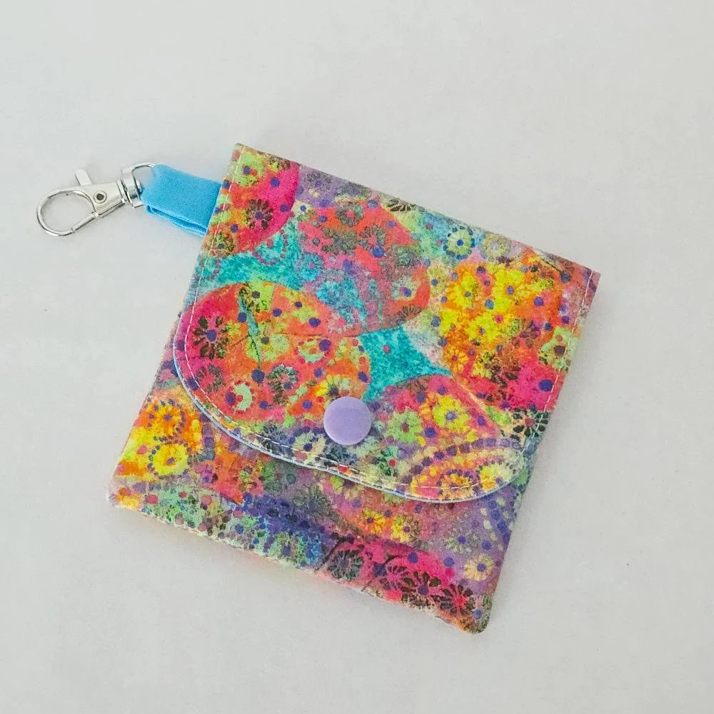 Handmade Bright Floral Wallet with three pockets, a snap closure, and a lobster claw clasp. Made from fabric with a vibrant floral pattern and a coordinating blue lining.