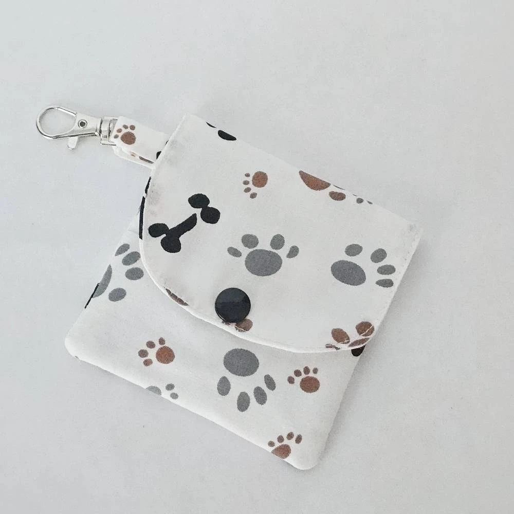 Handmade dog paw print wallet with three pockets, a snap closure, and a lobster claw clasp, made from 100% cotton fabric featuring gray and brown paw prints and black dog bones.